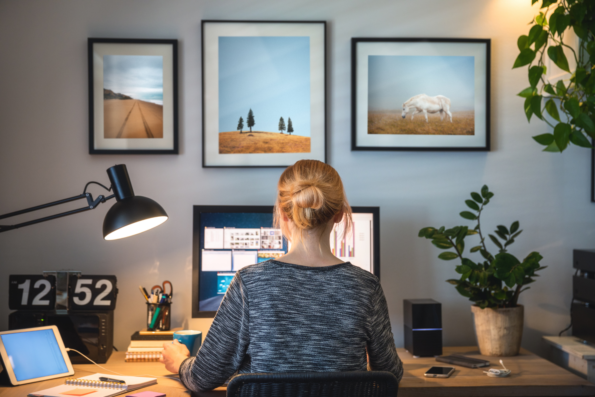 A woman sitting at a desk in front of framed pictures.