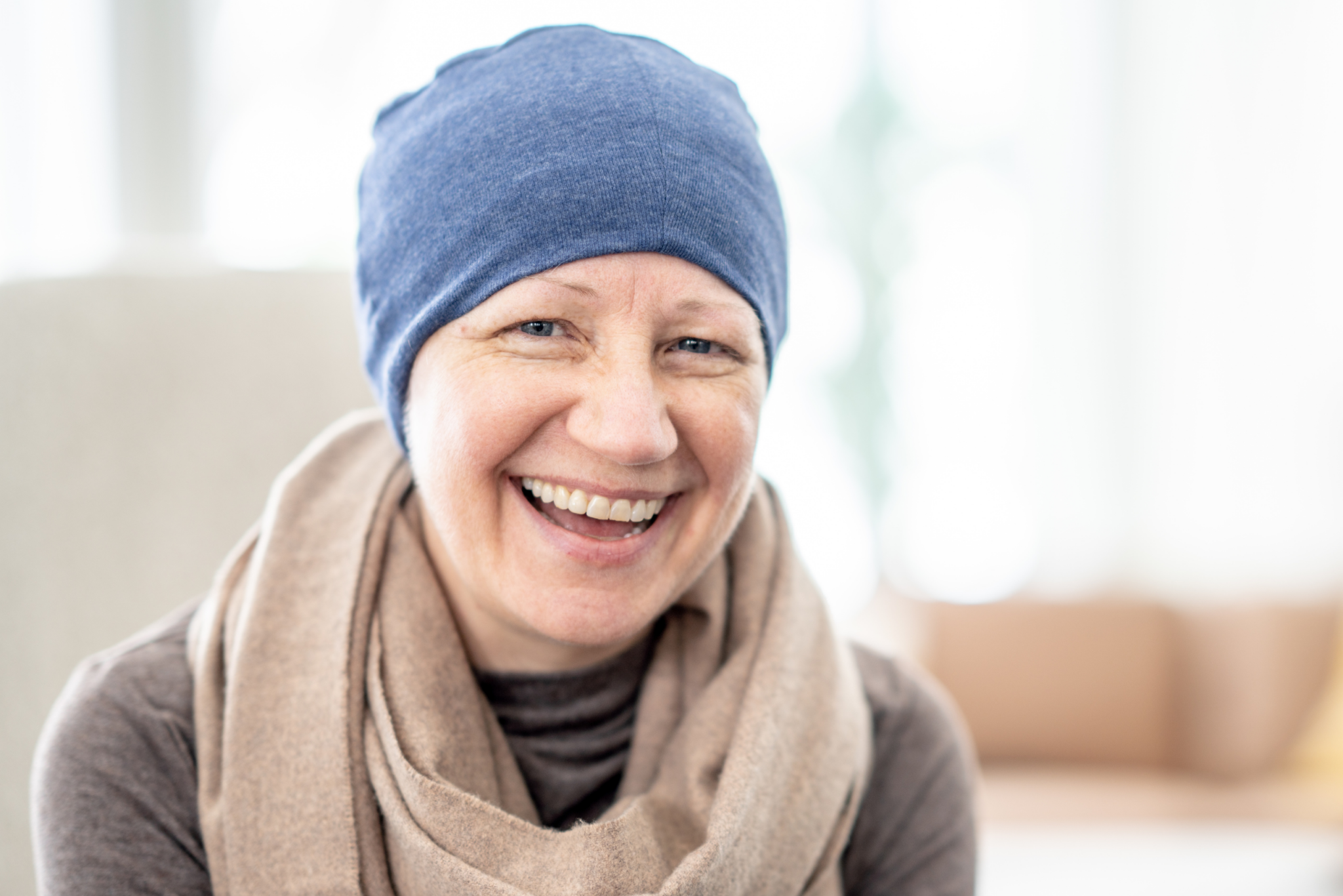 A woman wearing a blue hat and scarf is smiling.